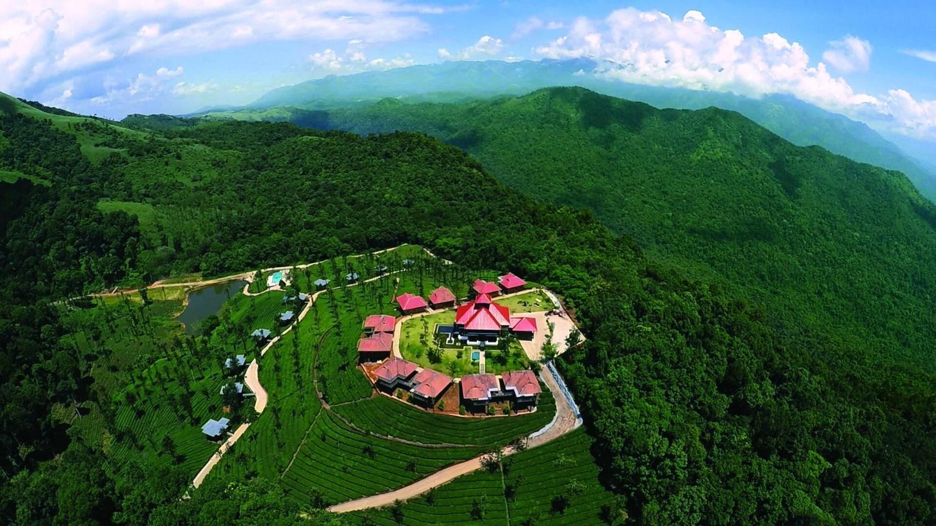 An aerial view of a resort with a central building surrounded by terraced gardens and a lake.