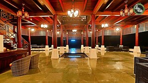 A spacious indoor area with a central reflective floor, wooden beams, and multiple chandeliers. - Wild Planet Resort (Nilambur)