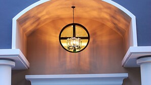 A building entrance with a large arched doorway, a glass door with an exit sign, and a hanging light fixture. - The Green View Hotel (Bang Sao Thong)
