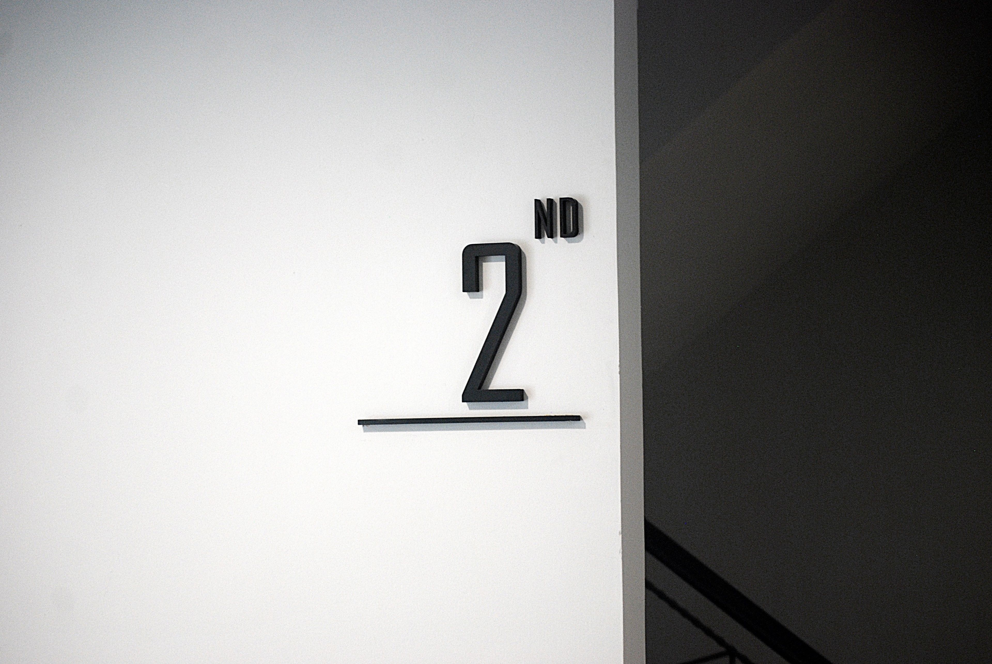 Een minimalistisch bord met het cijfer '2' en de letters 'ND' op een witte achtergrond.