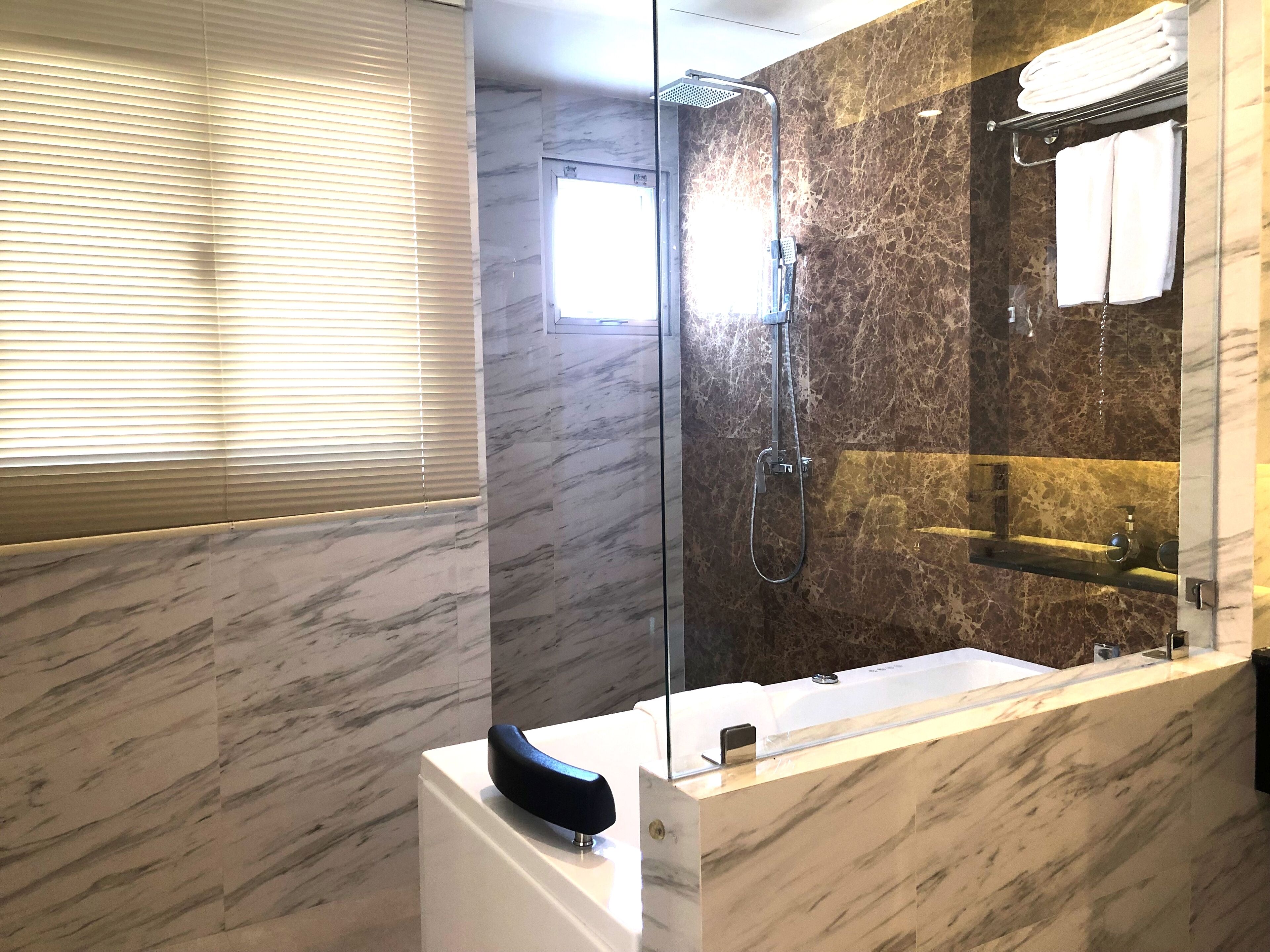 Un baño moderno con ducha envuelta en vidrio, un espejo grande y un tocador con azulejos de mármol.