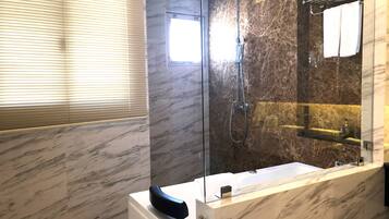 Un baño moderno con ducha envuelta en vidrio, un espejo grande y un tocador con azulejos de mármol.