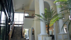 A spacious lobby with a grand staircase, large columns, and a palm tree. - The Green View Hotel (Bang Sao Thong)