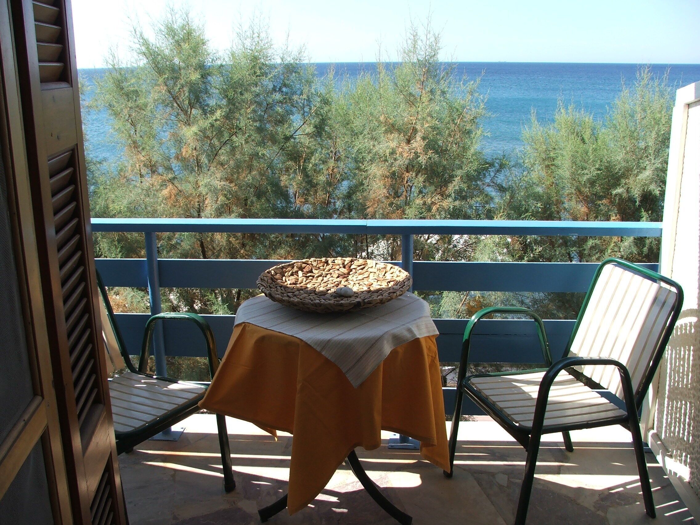 A balcony with a table, chairs, and a view of the sea.