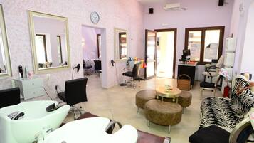 Experience a stylish salon with two large mirrors, a hair washing station, and a cozy seating area.