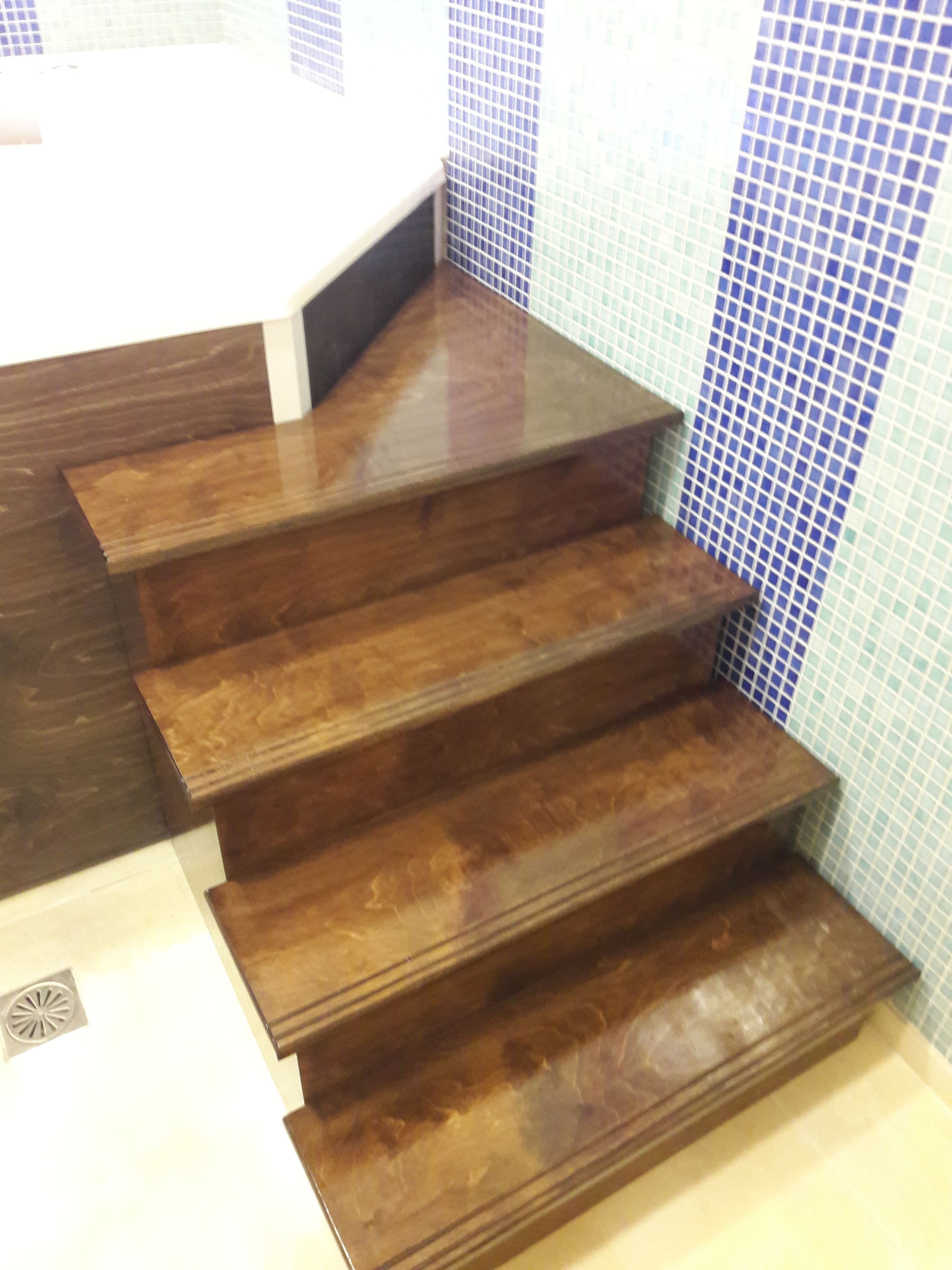 Eine Treppe aus Holz mit dunkler Oberfläche, die zu einem gefliesten Bereich führt.