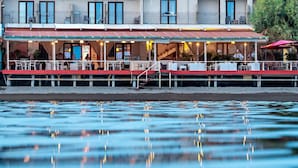 Een restaurant aan het water met terrasplekken, een overdekt terras en uitzicht op het water.