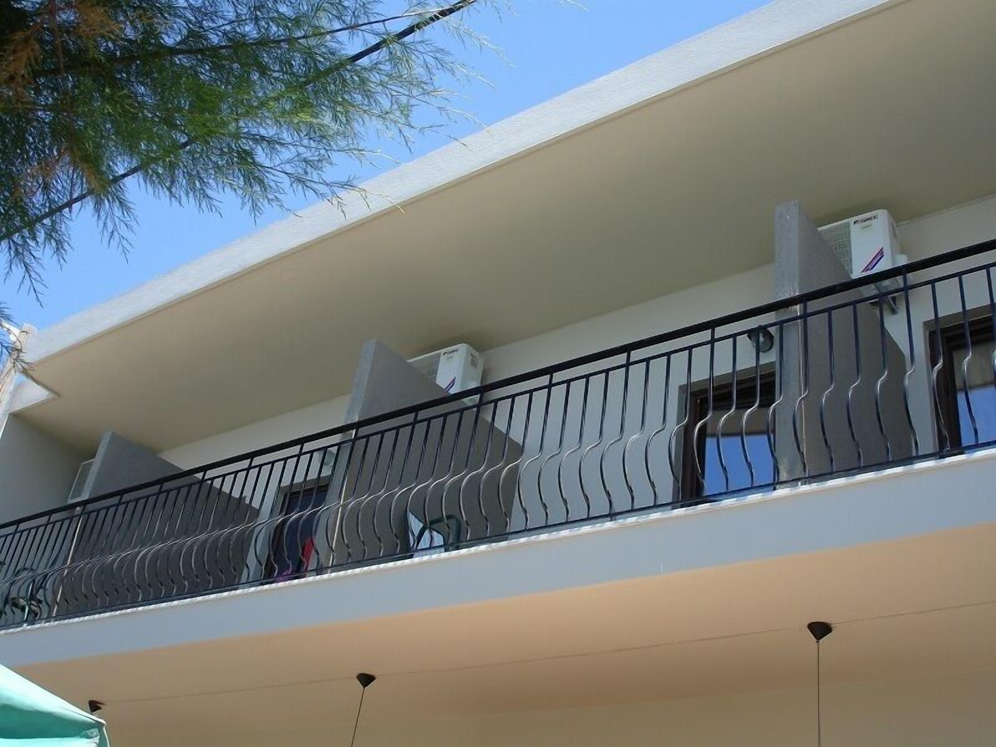 Un immeuble à plusieurs étages doté d’un balcon avec une rambarde en métal.
