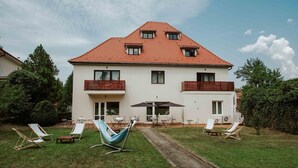 A two-story house with a red-tiled roof, a balcony on the second floor, and a patio area with outdoor furniture. - Hotel Republique (Sibiu)