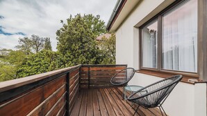 A wooden deck with a glass table and two chairs, overlooking a forested area. - Hotel Republique (Sibiu)