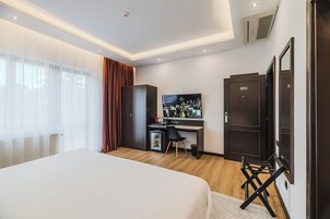 Una habitación de hotel moderna con una cama grande, un escritorio con ordenador, televisor y armario.