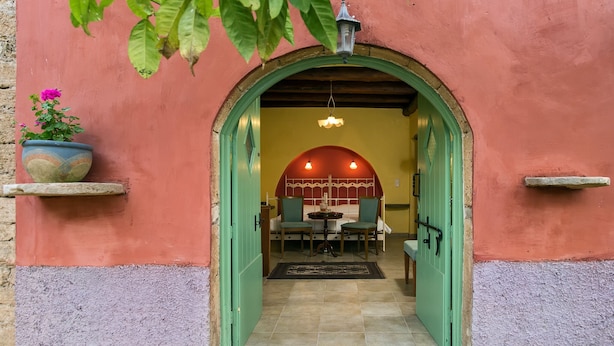 An arched doorway leading into a room with a bed, a table, and chairs. - Villa de Loulia Hotel (Corfu)