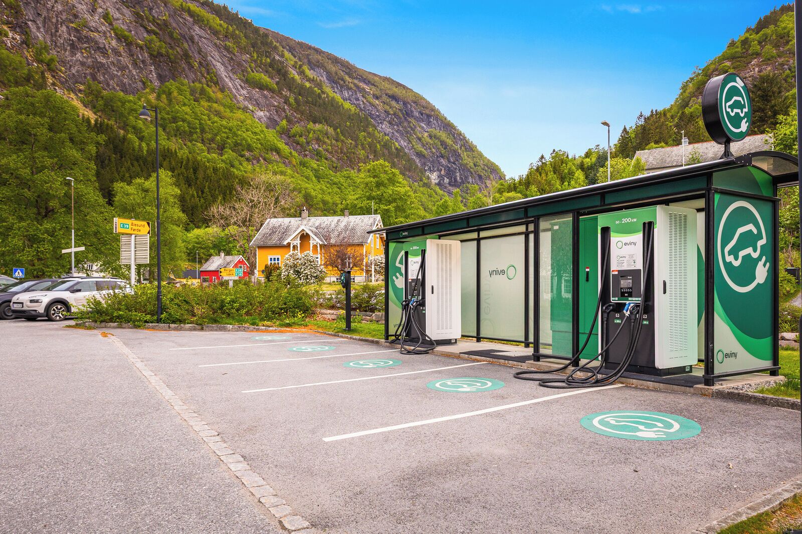 Eine grüne Ladesäule für Elektroautos vor einer Bergkulisse.