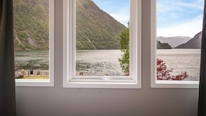 A room with three windows overlooking a lake and mountains. - Sogn Hotel (Vadheim)