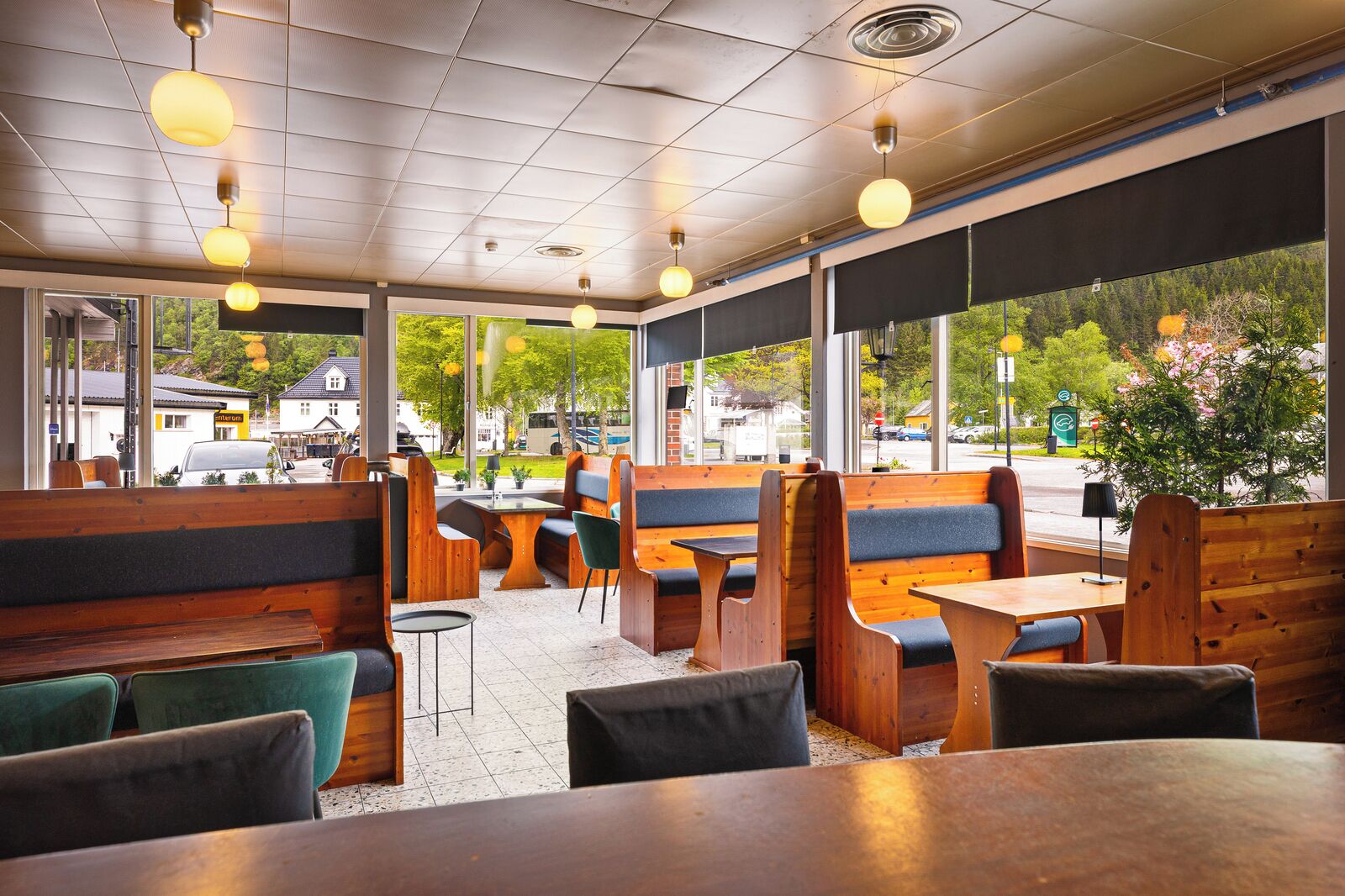 A restaurant interior with wooden booths, tables, and hanging pendant lights.