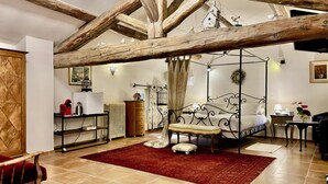 A bedroom with a four-poster bed, a red rug, and a wooden wardrobe. - Maison Bersane (Le Poujol-sur-Orb)