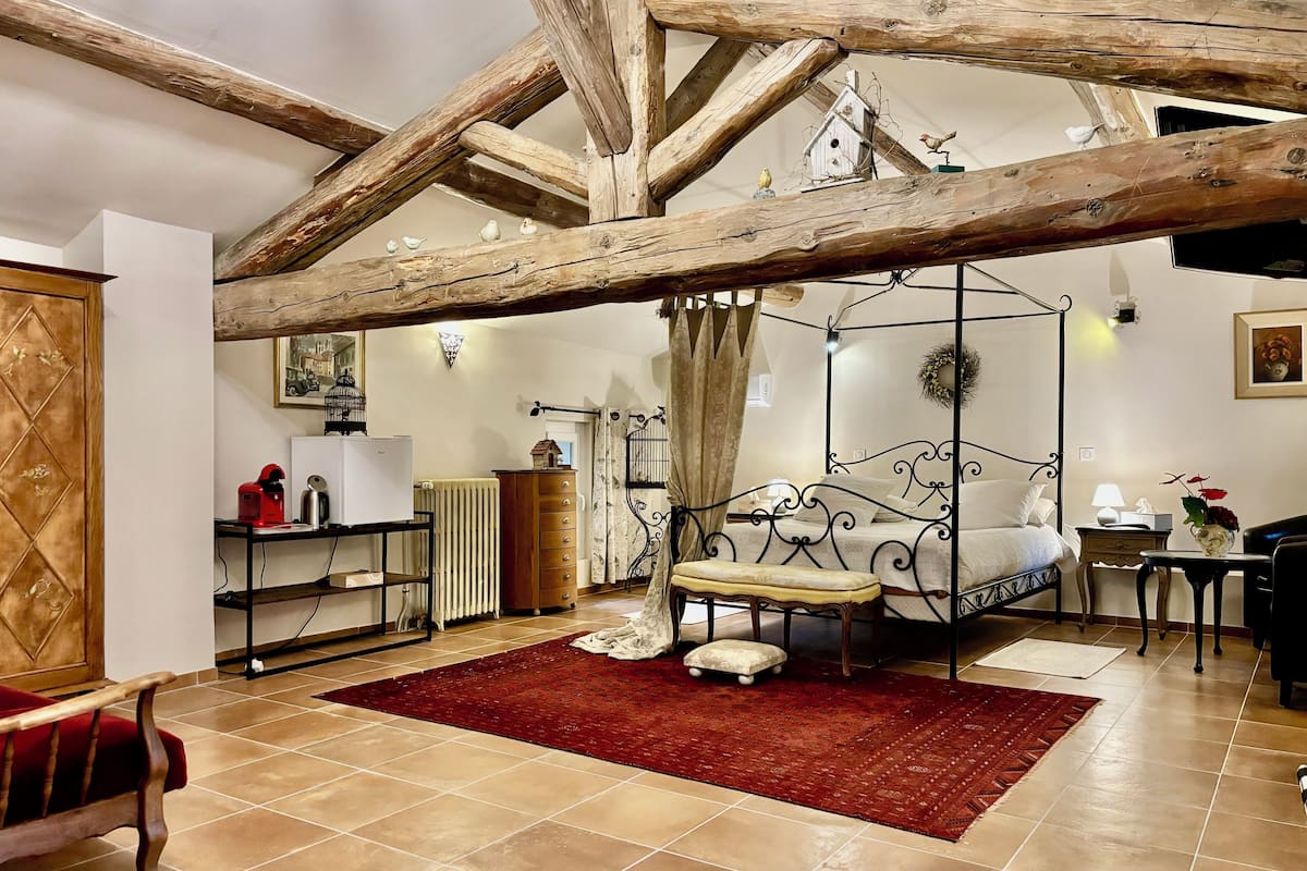 Un dormitorio con una cama con dosel, una alfombra roja y un armario de madera.