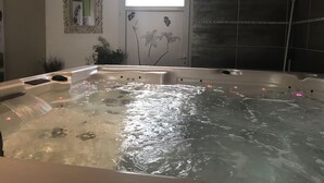 A hot tub with a control panel, a window, and a door with floral decorations. - Maison Bersane (Le Poujol-sur-Orb)