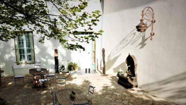 An outdoor patio with stone flooring, a round table, and chairs. There is a window with a view of the outside. - Maison Bersane (Le Poujol-sur-Orb)
