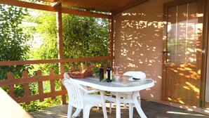 A covered patio with a white table and chairs, a basket, and a bottle of wine. - Tenuta De Fanti Agriturismo (Bibbona)