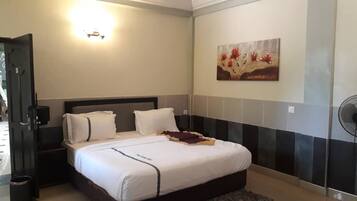 A hotel room with a bed, bedside tables, a wall-mounted artwork, and a ceiling fan.
