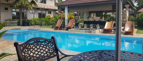 A swimming pool with lounge chairs and a gazebo.