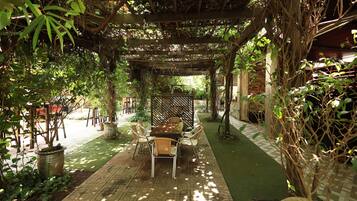 An outdoor patio with a pergola, seating area, and potted plants.