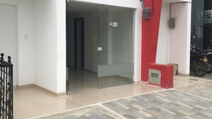 A modern building with a glass entrance, a red pillar, and a tiled floor. - Barcelona Hotel (Montería)
