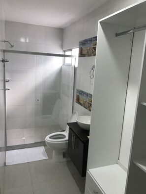 A modern bathroom with a glass-enclosed shower, a toilet, and a sink. - Barcelona Hotel (Montería)
