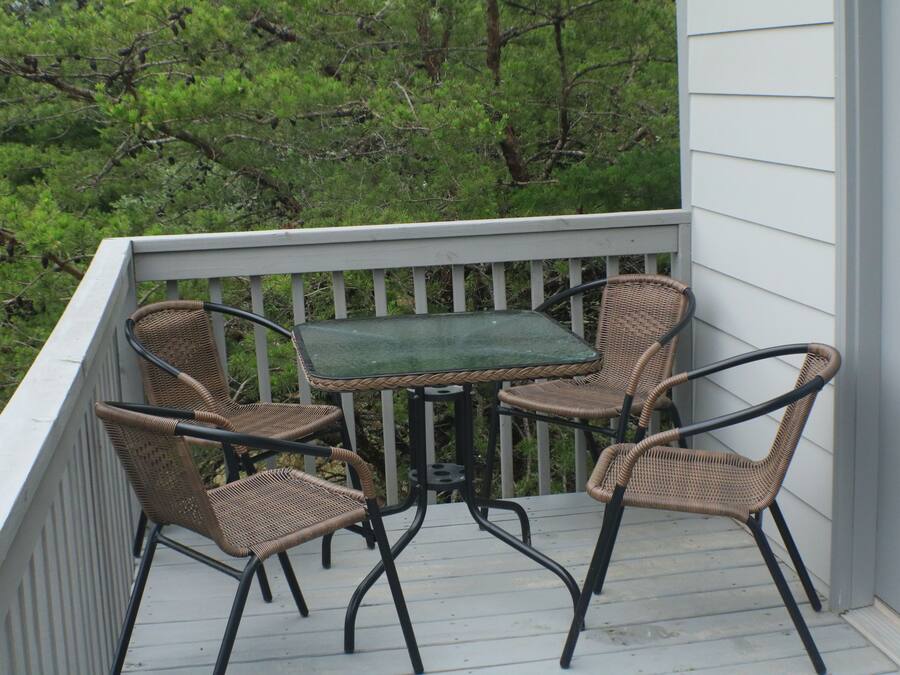 A balcony with a table and four wicker chairs.