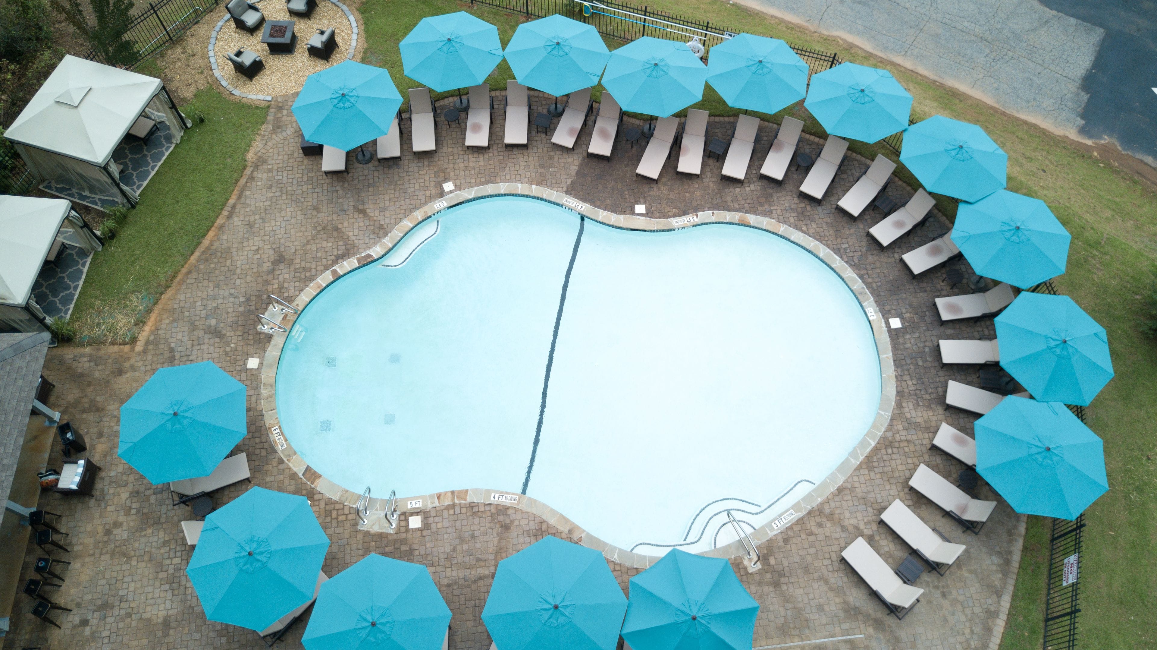 A large oval-shaped swimming pool surrounded by lounge chairs and umbrellas.