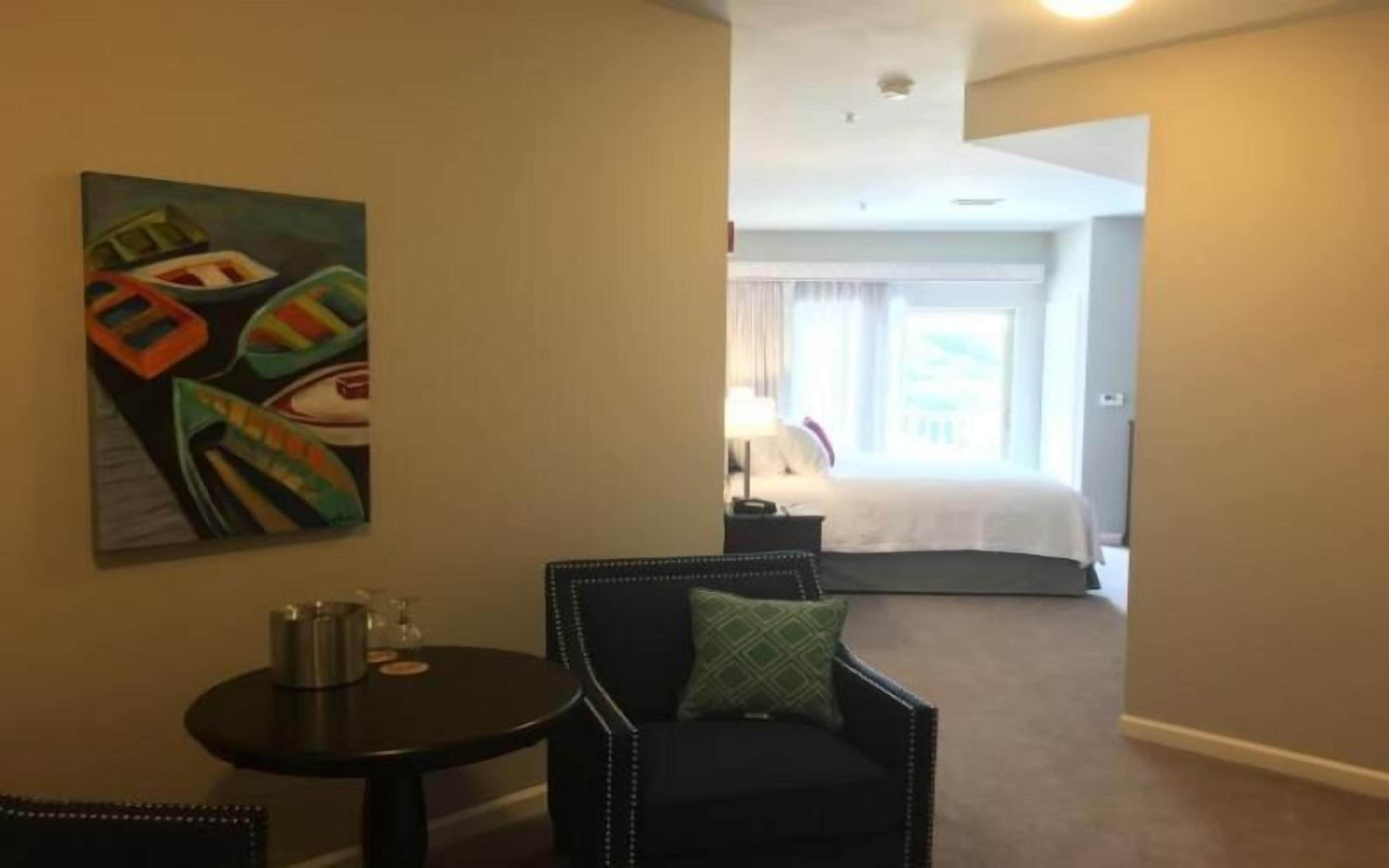 A hotel room with a bed, a nightstand, a lamp, and a painting on the wall.