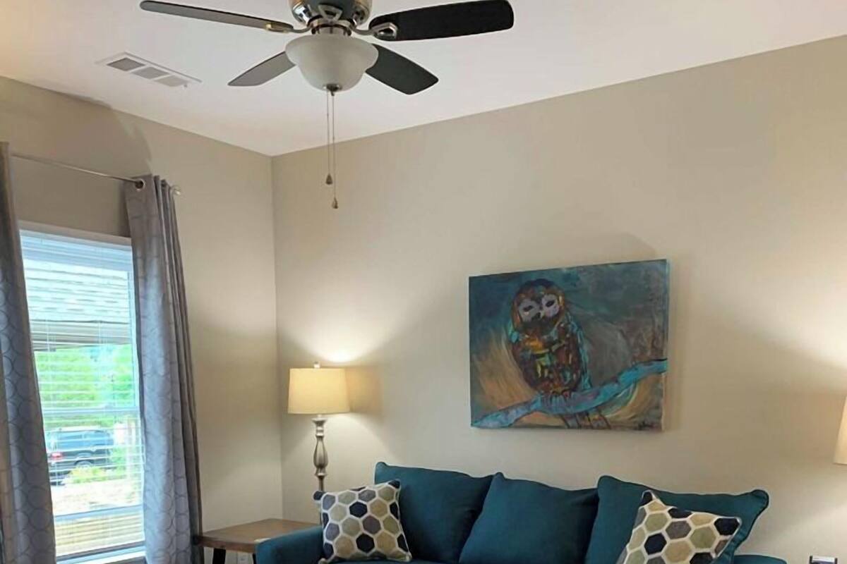 A living room with a sofa, coffee table, and a ceiling fan.