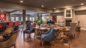 Een ruime woonkamer met een open haard, comfortabele zithoek en een eethoek met rode stoelen.