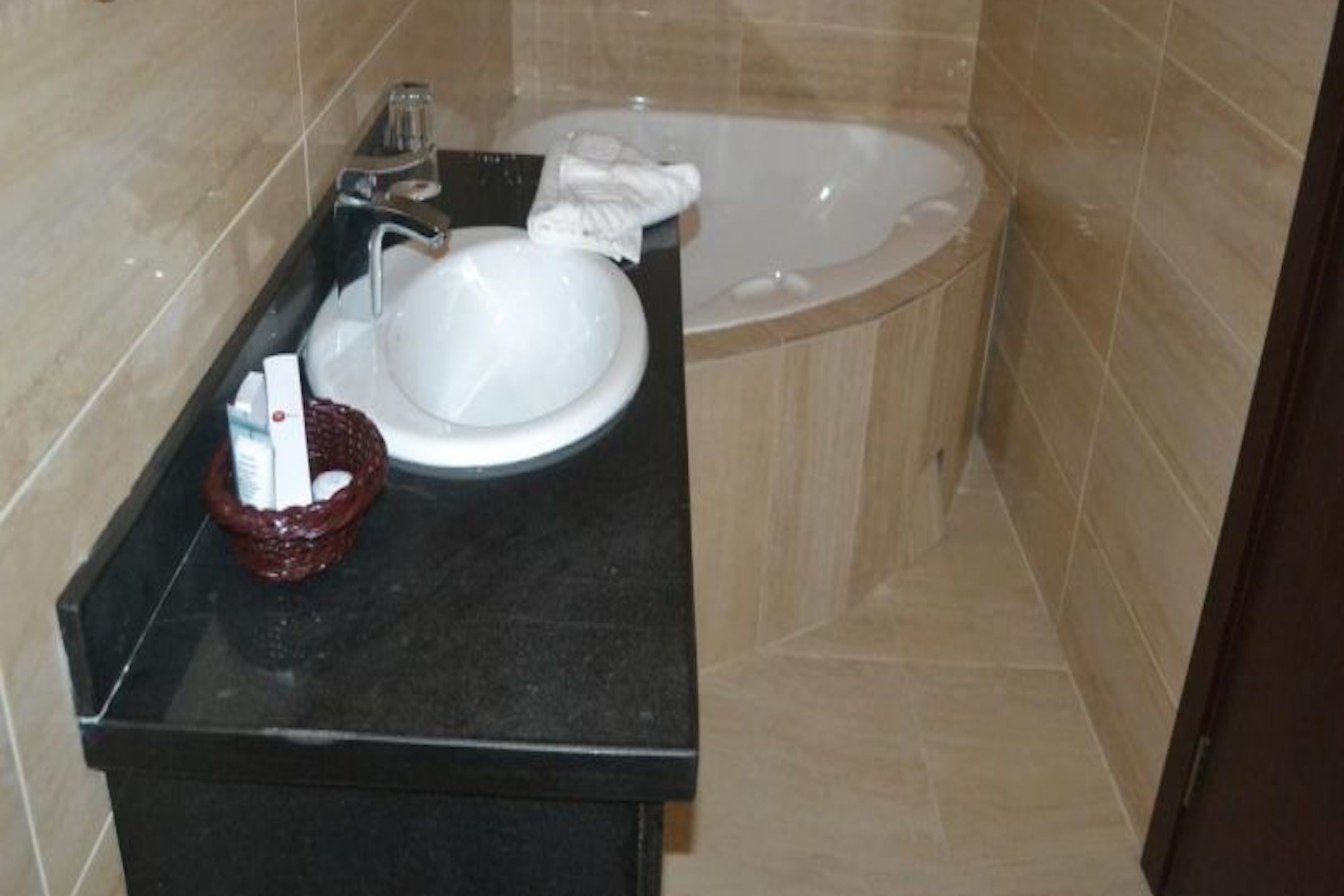 A bathroom with a white sink, a black countertop, and a bathtub.