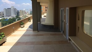 A balcony with a city view, potted plants, and a seating area. - Apartamento Ejecutivo Ancora (Barranquilla)