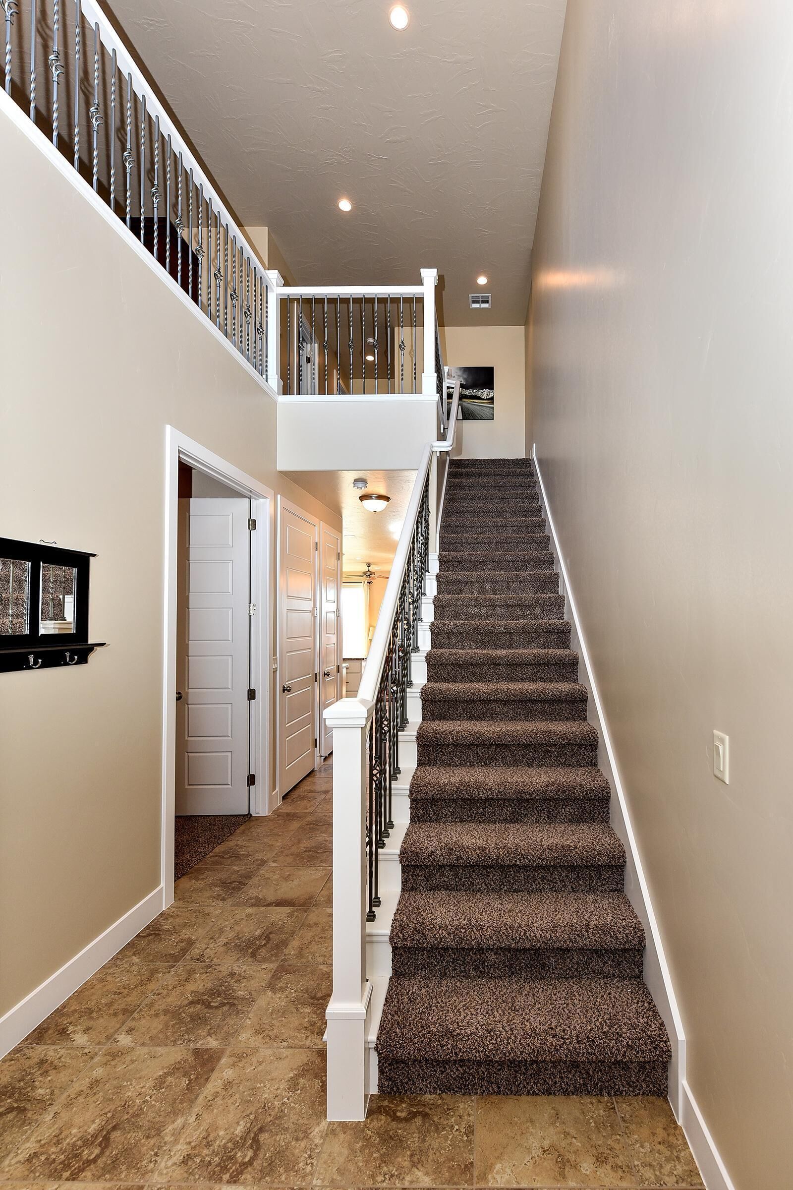 A multi-level staircase with carpeted steps and white railings, leading to a second-floor landing.