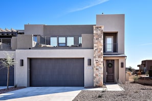 A modern two-story house with a garage, a balcony, and a stone accent wall.