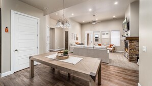 A spacious living room with a wooden dining table, a fireplace, and a sofa set. - Snow Canyon Hideaway (St. George)