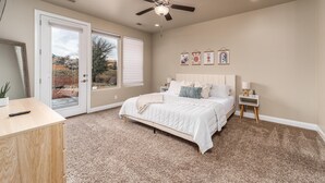 A bedroom with a bed, a ceiling fan, a nightstand, and a desk. - Snow Canyon Hideaway (St. George)