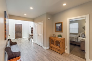 A hallway with a bench, wooden cabinet, and a bed in the adjacent room. - Mi Casa Es Su Casa (St. George)