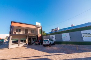 Un hotel moderno con un letrero llamativo, una zona de estacionamiento techada y una pared con carteles de eventos.
