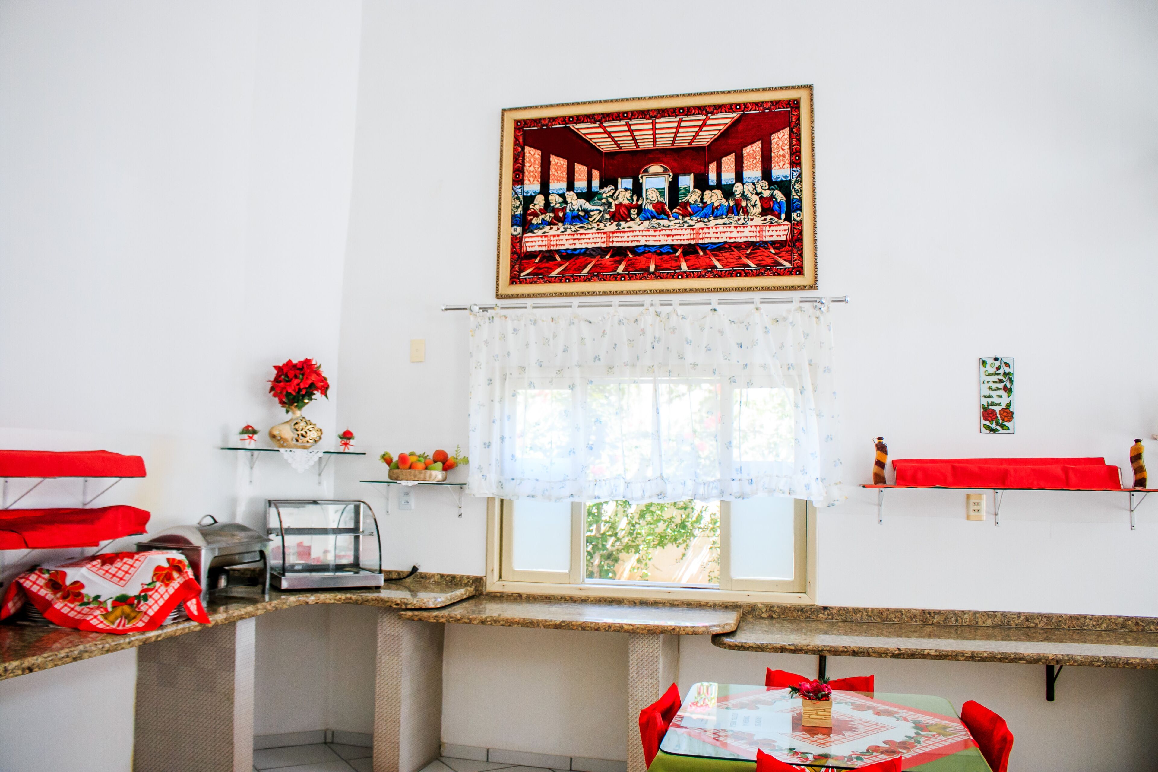 Un comedor con una mesa larga, sillas, una ventana con cortina y un cuadro sobre la ventana.