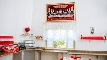 Un comedor con una mesa larga, sillas, una ventana con cortina y un cuadro sobre la ventana.