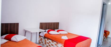 A hotel room with two beds, a small table, and a mirror.