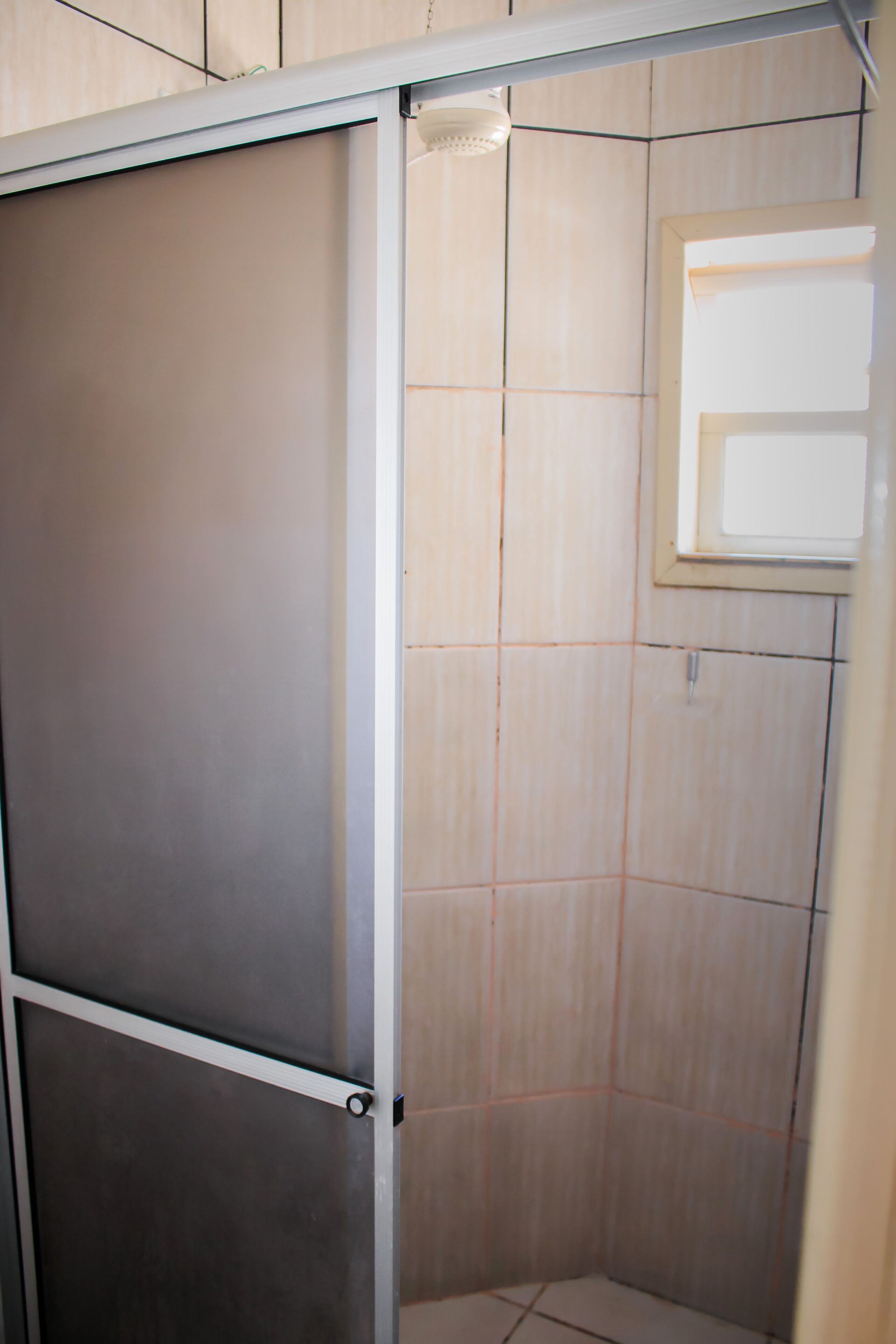 A shower enclosure with a frosted glass door and a small window.