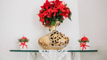 Un jarrón decorativo con flores rojas sobre un estante de vidrio.