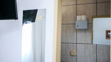 A bathroom with a mirror, a towel rack, a toilet paper holder, and a light switch.