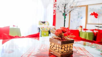 Une table agrémentée d’un élément décoratif central en bois sculpté, d’une nappe rouge et d’une ambiance festive avec des touches de rouge et de vert.