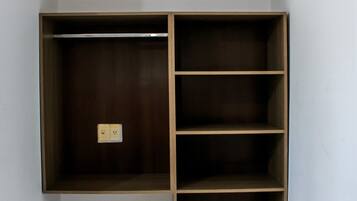 A corner closet with wooden shelving and a power outlet.
